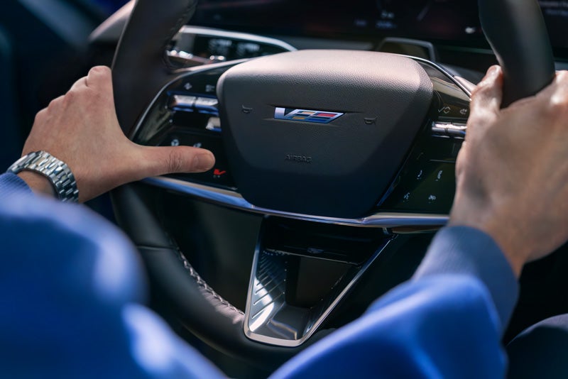 Close-up of a Man About to Press the V-Button on the 2026 OPTIQ-V Steering Wheel | Bergstrom Cadillac of Green Bay in Green Bay WI