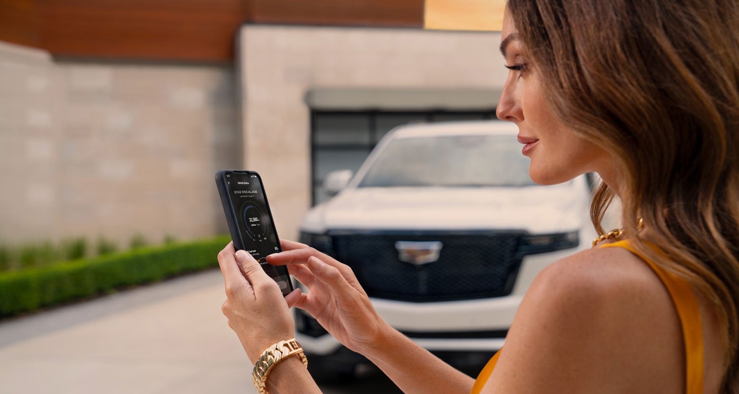 lady checking her mobile with a Cadillac vehicle background | Bergstrom Cadillac of Green Bay in Green Bay WI